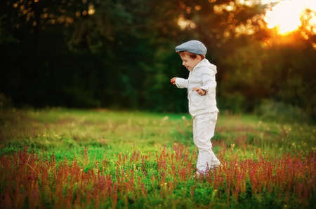 boy in a white suit walking in a meadow with wild flowersの写真素材