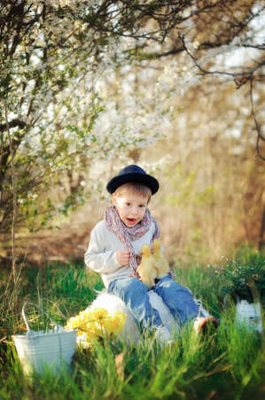boy sitting outdoors in a hat with ducks and chickensの写真素材