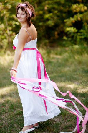 outdoors woman in a white dress with colored ribbonsの写真素材