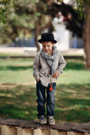 in the park on a stone fence is a boy in jeans and a hatの写真素材
