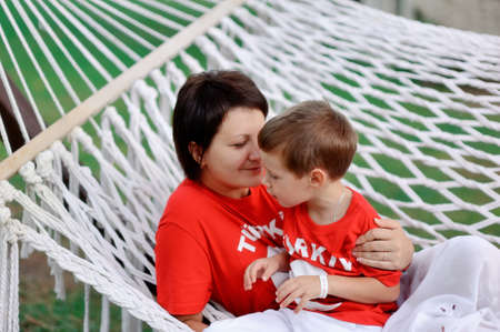 outdoors in a white hammock relax the mother and son in kasnyh shirtsの写真素材