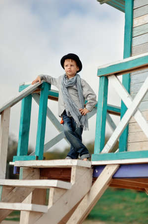 on the wooden stairs is an emotional boy in a black hat with a scarfの写真素材