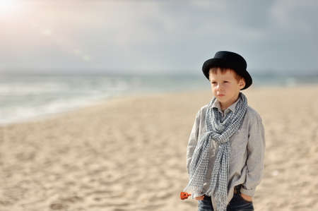 on the shore is thoughtful boy in a black hat with a scarfの写真素材