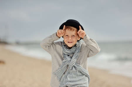 emotional boy in black hat and jeans posing on the beachの写真素材