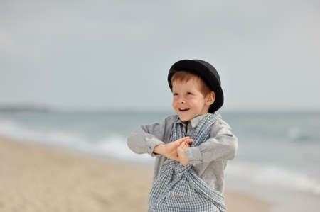 emotional boy in black hat and jeans posing on the beachの写真素材