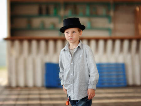 beautiful child in a black hat and jeans posing on a wooden floorの写真素材