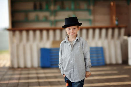 beautiful child in a black hat and jeans posing on a wooden floorの写真素材