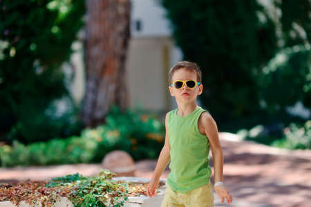 boy in sunglasses and a green shirt walking in the parkの写真素材
