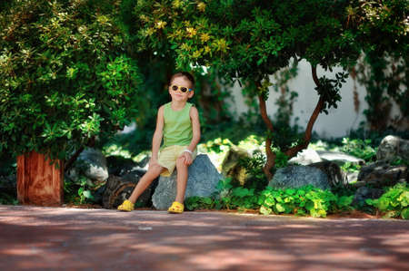 boy in sunglasses and a green shirt walking in the parkの写真素材