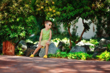 boy in sunglasses and a green shirt walking in the parkの写真素材