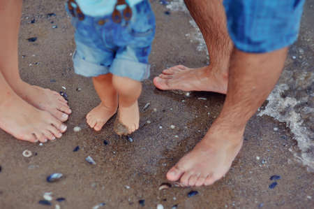 on the beach in the sand with shells barefoot familyの写真素材