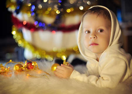 portrait of a boy in a cap mittens on New Year s background with toysの写真素材