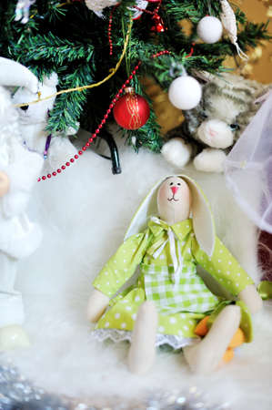 under the Christmas tree on a white rabbit sitting in a green dressの写真素材
