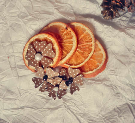 On a white table are dried orange segments and paper flowersの写真素材