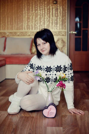 girl in a warm, white suit with flowers poses in home comfortの写真素材