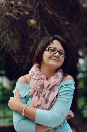 portrait of a woman posing in a blue sweater and glassesの写真素材