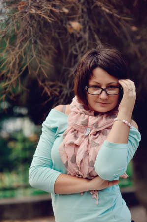 portrait of a woman posing in a blue sweater and glassesの写真素材