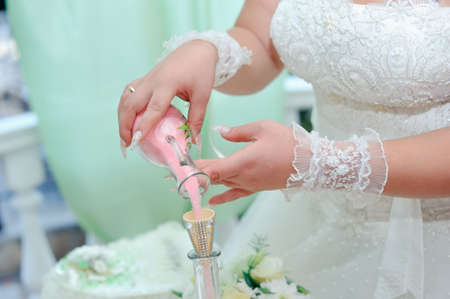 Beautiful bride s hands poured colored sand into a bottleの写真素材