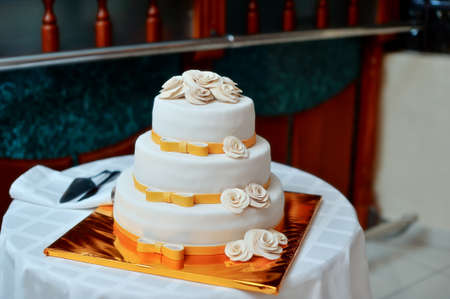 high white wedding cake with beautiful flowers on a golden pedestalの写真素材