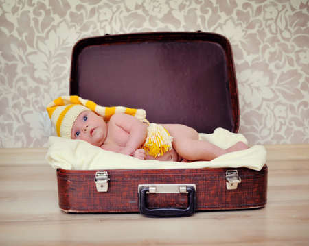 naked baby in a warm hat is in the suitcaseの写真素材