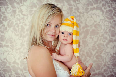 delicate and feminine mother tenderly hugging her baby in the capの写真素材