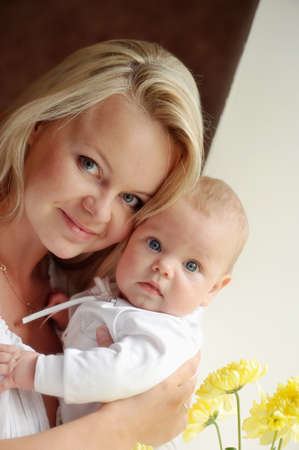 feminine mother tenderly embracing her child at the window with flowersの写真素材