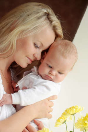 feminine mother tenderly embracing her child at the window with flowersの写真素材