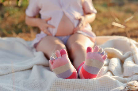 outdoors sitting pregnant woman with colored socks on feetの写真素材