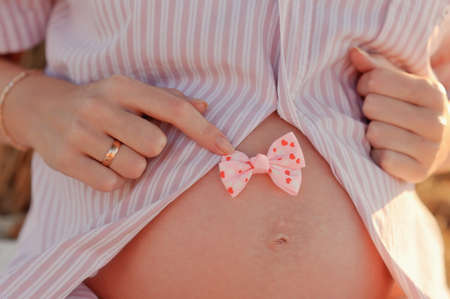on the abdomen of a pregnant woman pink bowの写真素材
