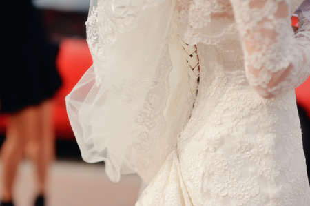elegant bride in a beautiful white lace dress and veil view from the backの写真素材
