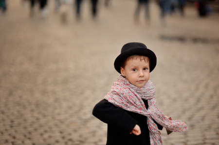 stylish, thoughtful boy in a black coat and hat with a beautiful scarfの写真素材