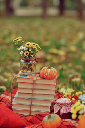 outdoors ripe pumpkin and a stack of books with a bouquet of autumn flowersの写真素材