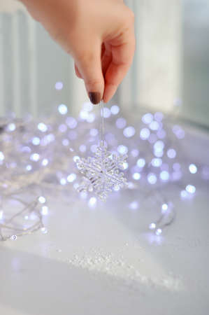 amid garlands of lights female hand holds a toy snowflake