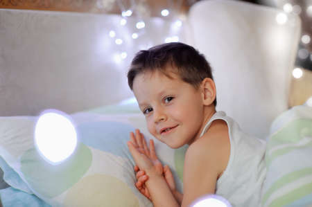 the little boy woke up in a children s cozy bed of lightsの写真素材
