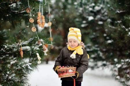 snowy winter outdoors boy dresses up Christmas tree bagels and toysの写真素材