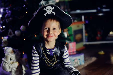 The boy in clothes of the pirate against a New Year tree posesの写真素材