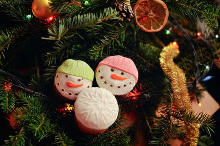 Against abstract sparks of garlands a fruitcake in the form of a snowmanの写真素材