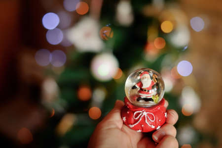 Against a New Year tree in a hand a sphere with Santa Clausの写真素材