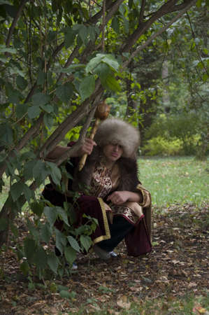 The young man in a theatrical suit of a nobleman and in a fur cap poses on the natureの写真素材