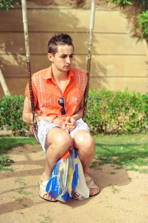 Adult guy in a baby swing recalls childhoodの写真素材