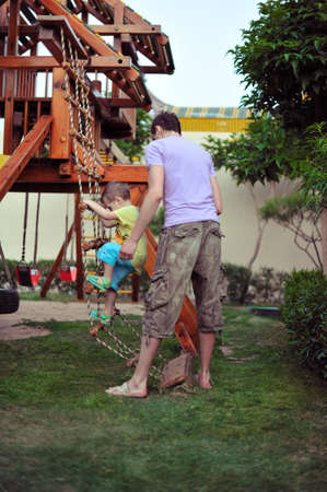 outdoors on summer vacation father and son on a swingの写真素材