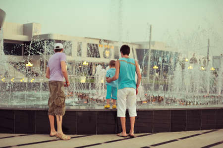 near the beautiful fountain walking people in a spray of waterの写真素材