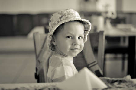 in the room at the table sits a boy in a hatの写真素材