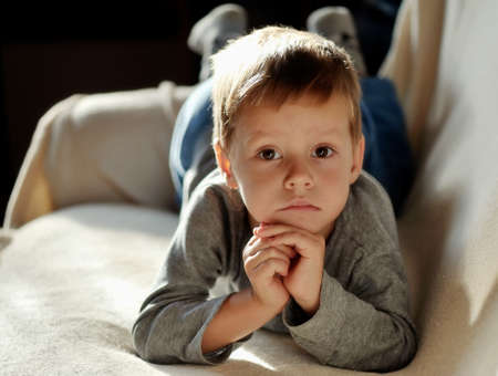 on the sofa lay a little boy in the sun than the upsetの写真素材