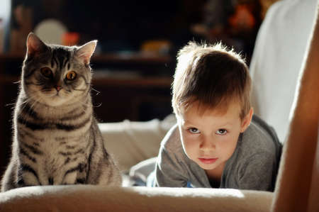 in a room on the sofa lay a boy with black catの写真素材