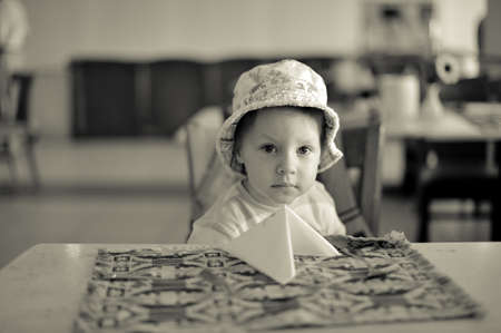 in the room at the table sits a boy in a hatの写真素材