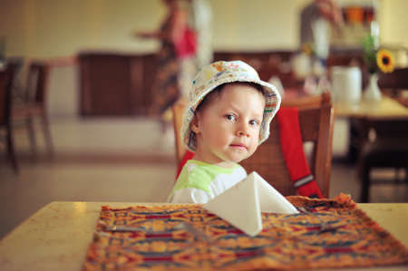 in the room at the table sits a boy in a hatの写真素材