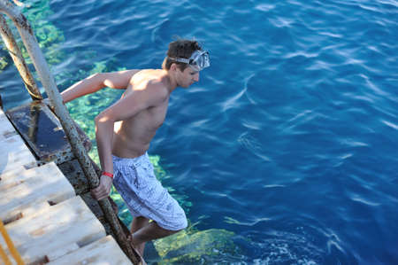 guy in a mask prepares to jump from a springboard into the waterの写真素材