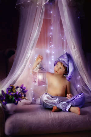 boy in pajamas and a purple hat sitting in the shed with a flashlightの写真素材