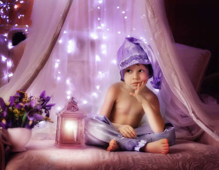 boy in pajamas and a purple hat sitting in the shed with a flashlightの写真素材